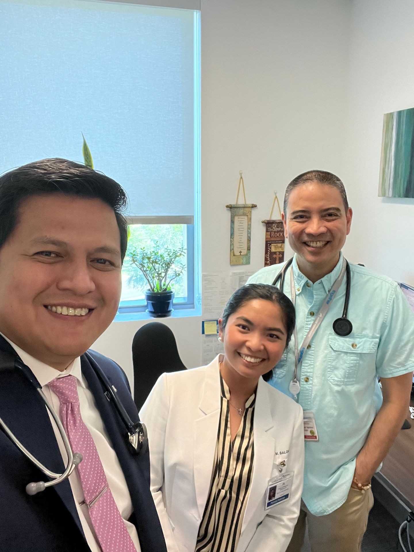 Three smiling healthcare professionals with stethoscopes in a well-lit office.